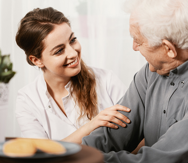 A photo of caregiver smiling to her elderly patient