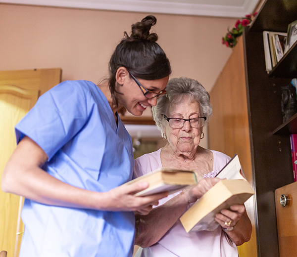 A photo of elderly and nurse reading a book